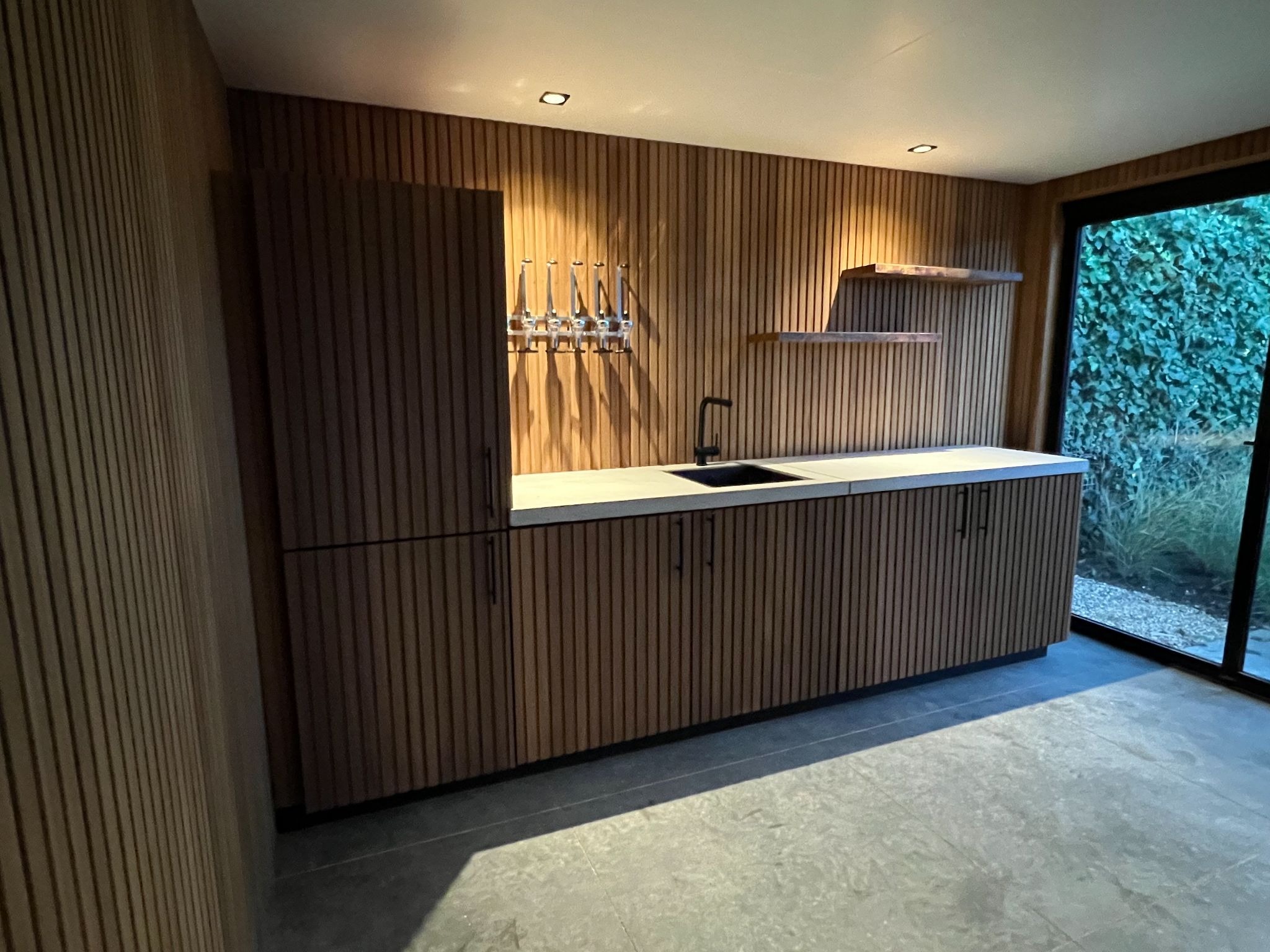 Luxe buitenkeuken met Ayous houtafwerking en zicht op tuin